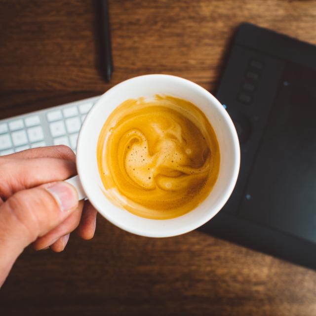 Photo of coffee in a cup being held above a desk